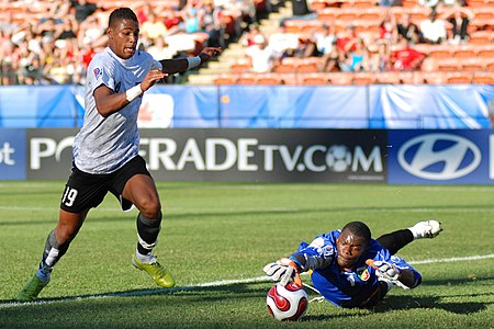 Avusturyalı futbolcu Rubin Okotie 2007 FIFA 20 Yaş Altı Dünya Kupası'nda Kongolu kaleci Destin Onka'ya karşı gol atmaya çalışırken. Pozisyon sonunda Onka topu kurtarabilmeyi başarmıştır. (Üreten:Nwieberesmi)
