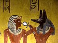 «Anubis gir livsånde til Thutmosis IV», freske i gravkammeret KV 43 i Kongenes dal fra 18. egyptiske dynasti. Anubis, guddom for dødsriket og balsamering, ble framstilt som sjakal, gjerne med menneskekropp og klaftformet løvemanke. Hankekorset var livssymbol.