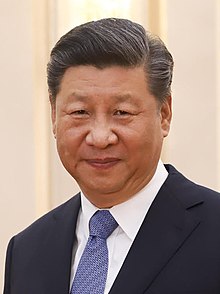 Head shot of Xi Jinping in 2019. He is wearing a black suit jacket, white shirt and a blue necktie.