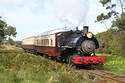 Steam locomotive No. 4 hauls a small tourist train down a straight portion of the railway