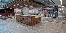 A wooden desk emblazoned with the Texas A&M logo situated next to a coffee table and chairs, and a mirrored wall with Texas A&M values printed across it.