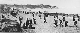 American troops land on an Algerian beach during Operation Torch. Near Algiers, "Torch" troops hit the beaches behind a large American flag "Left" hoping for the French Army not fire... - NARA - 195516.jpg