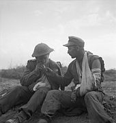 A captured German and a wounded British soldier share a cigarette after the battle The British Army in Tunisia 1943 NA1344.jpg