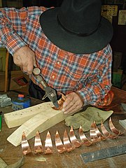 Zingueur en cours de fabrication d'une girouette en cuivre.