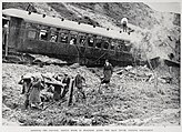 A passenger is carried off in a stretcher with the train wreck in the background