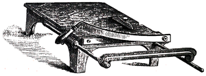 Cross-hatched image of a flat platform on four short legs with a guillotine-blade at one end.