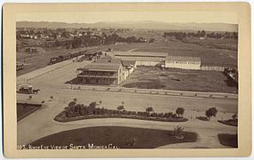 Sépia. Vue aérienne. Au loin, les montagnes. À gauche, on aperçoit la vieille gare et au centre quelques bâtiments.