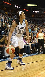 full height portrait of a young woman with long dark hair pulled back, wearing uniform that says «Lynx 23»