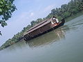 A houseboat moves through Ashtamudi Lake. Munroe island in the background.