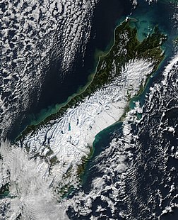 Vue satellite de la NASA au-dessus de l’île du Sud (Nouvelle-Zélande) après une puissante tempête de neige en juin 2006 montrant, les Alpes du Sud et les bassins versants à l’est de l’île, enneigés. L’image montre également sur la West Coast les eaux chargées de sédiments provenant des torrents se déversant dans la mer de Tasmanie après les fortes pluies que connut l’île. (définition réelle 2 600 × 3 200)