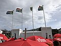 Red umbrellas with "sex work is work" written on them, against the backdrop of the SA flags outside South Africa's Parliament in Cape Town.