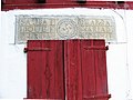 Structural lintel with a lauburu and founders' names, above traditional Basque houses in Lower Navarre, Spain