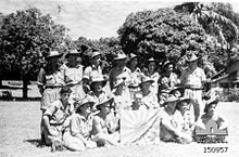 A group of soldiers in slouch hats pose with a Japanese flag