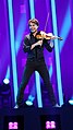 Full-body colour photograph of Alexander Rybak performing on the Eurovision Song Contest 2018 stage with violin.