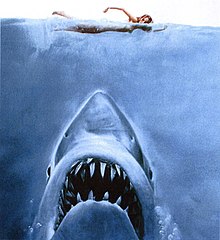 Cover art for the novel Jaws, also used for its movie adaptation. The art features a shark approaching a swimmer from below.