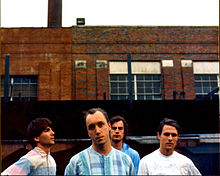 The band members in front of an industrial building