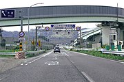 東名阪道出口より接続する国道25号名阪国道の起点を望む。道路両側に0キロポストが見える。