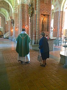 A Lutheran priest of the Church of Sweden prepares for the celebration of Mass in Strangnas Cathedral Strangnas Cathedral interior.jpg