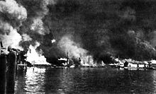 Sangley Point Cavite Navy Yard burning after a Japanese air attack on December 10, 1941. Small-arms shells explode (left) and a torpedo-loaded barge (center) burns. Cavite Navy Yard burning 10 Dec 1941.jpg