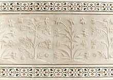 Example of carved flower reliefs on marble and pietra dura (parchin kari) inlaid stonework above and below, at the Taj Mahal Detail of plant motifs on Taj Mahal wall.jpg