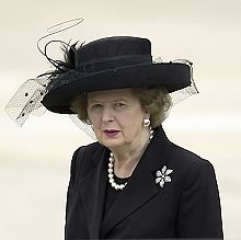 Thatcher in a black suit and hat, with a solid white background.