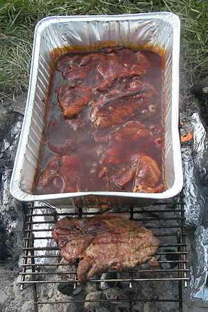 Pork steaks cooking over a charcoal fire