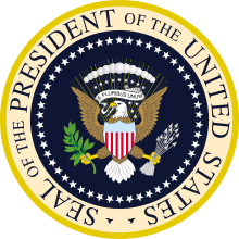 Dans un cercle, un aigle est représenté au centre avec divers symboles dont un blason aux couleurs des États-Unis, et autour de ce dessin il est écrit en anglais : sceau du président des États-Unis d'Amérique.