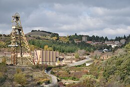 Chevalet de mine abandonné dans un site minier où la végétation reprend ses droits.