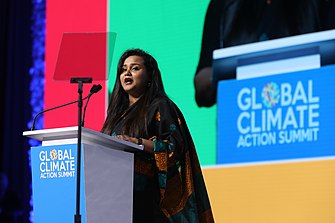 Wickramanayake is speaking at a podium, and the podium has a blue banner reading "Global Climate Action Summit"