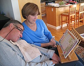 Muž s ALS komunikuje se svou ženou ukazováním na písmena a slova pomocí laserového ukazovátka namontovaného na hlavě.