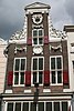 Pand met halsgevel met doorgaande pilasters, gebeeldhouwde vleugelstukken, festoenen, oeil-de-boeuf en jongere onderpui