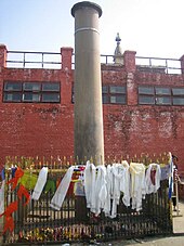Древний каменный столб, окруженный небольшой оградой, покрытый религиозной одеждой