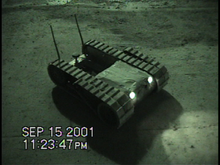 A PackBot Scout robot shown with its second pair of treads in the horizontal position. This robot is conducting search and rescue at ground zero after the 9/11 terrorist attacks. Packbot.PNG