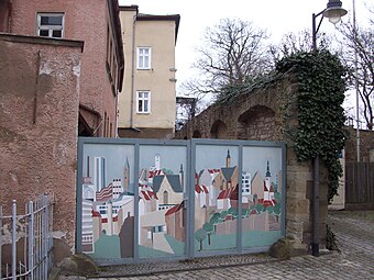 Nördliche Mauerreste der Reichsburg an der Kutschenstation von 1563, Burggasse 17 (vorne links, heute teil­rekonstruiert) mit zuge­mauer­ten, raumhohen Öffnungen. Blick von außen auf die Burgmauer