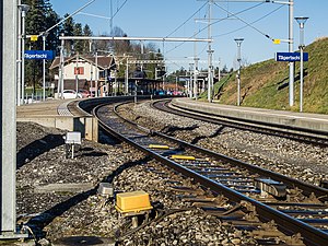 Two-story building with gabled roof next to double-tracked railway line