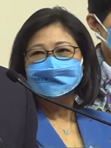 Janet Lam. Eine chinesische Frau in Blauer Bluse mit einer passenden Mund-Nasen-Maske. 2022.