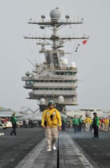 A catapult officer inspects the catapult track prior to flight operations on Abraham Lincoln with fellow shipmates in the background CVN72 Isola.jpg