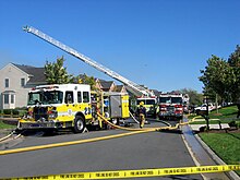 A photograph of a street in Ashburn, with a fire engine and fire fighters in teh foreground