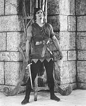 Douglas Fairbanks as Robin Hood Fairbanks Robin Hood standing by wall w sword.jpg