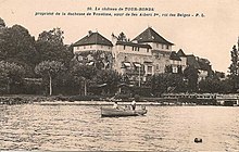 devant un château néo-gothique imposant, un plan d'eau sur lequel navigue un canot avec un rameur et un passager debout