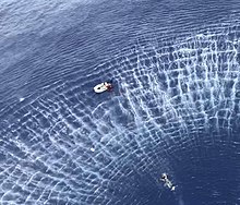 A US Navy rescue swimmer swims toward a stranded boat near Guam in 2019 Sailor swims toward a civilian in distress aboard a sailboat during a search and rescue mission near Guam. (48380723691).jpg