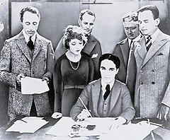 Zleva doprava David Wark Griffith, Mary Pickfordová, Charlie Chaplin (sedící) a Douglas Fairbanks podepisují roku 1919 smlouvu o založení filmové společnosti United Artists. Vzadu stojí právníci Albert Banzhaf (vlevo) a Dennis F. O'Brien (vpravo)