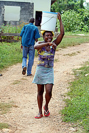 Young woman carrying a water bucket on her head, Clarendon, Jamaica.