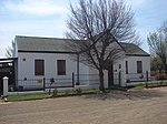 This T-shaped building has a pitched corrugated iron roof with side gables. It has a veranda in front This building was erected to house the C.N.O.-school, which was opened in 1904 in Reddersburg. It th Type of site: School Previous use: School. Current use: House. This building was erected to house the C. N. O.-school, which was opened in 1904 in Reddersburg. It therefore occupies an important place in the history of education in the town.