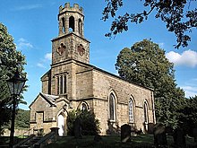 A single storey small church, constructed of sandstone, surrounded by trees