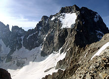 Photo en couleur d'une montagne large et abrupte, dentelée au sommet