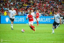 Theo Walcott dribbles past Gareth Barry and James McCarthy at the National Stadium in Singapore.