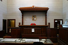 A judge's bench in a courtroom in Beechworth, Victoria, Australia, with the royal arms and Queen Victoria's portrait Bench Aus.jpg