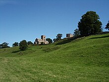 Grassy ground sloping upwards, with a stone-built church in the distance.