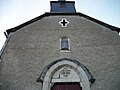 La façade de l'église avec une statue de la Vierge à l'Enfant protégée dans un coffret et une vitre.